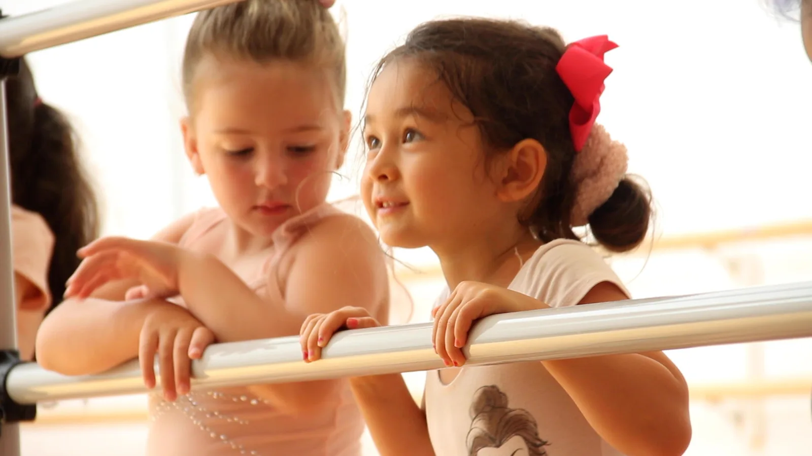 Two young dancers resting on the barre together during a Creative Movement class