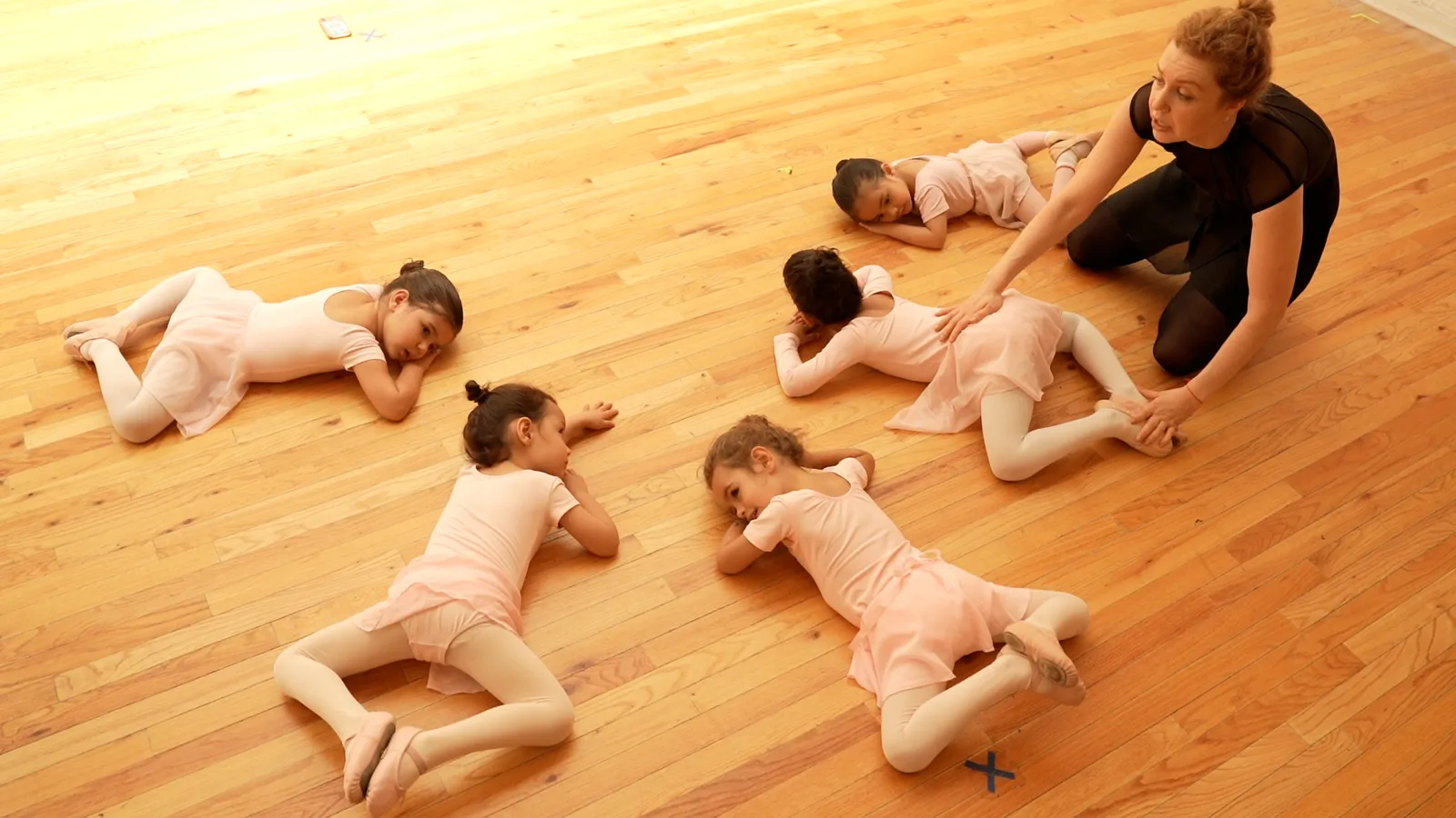 Children lying on the studio floor stretching with their teacher
