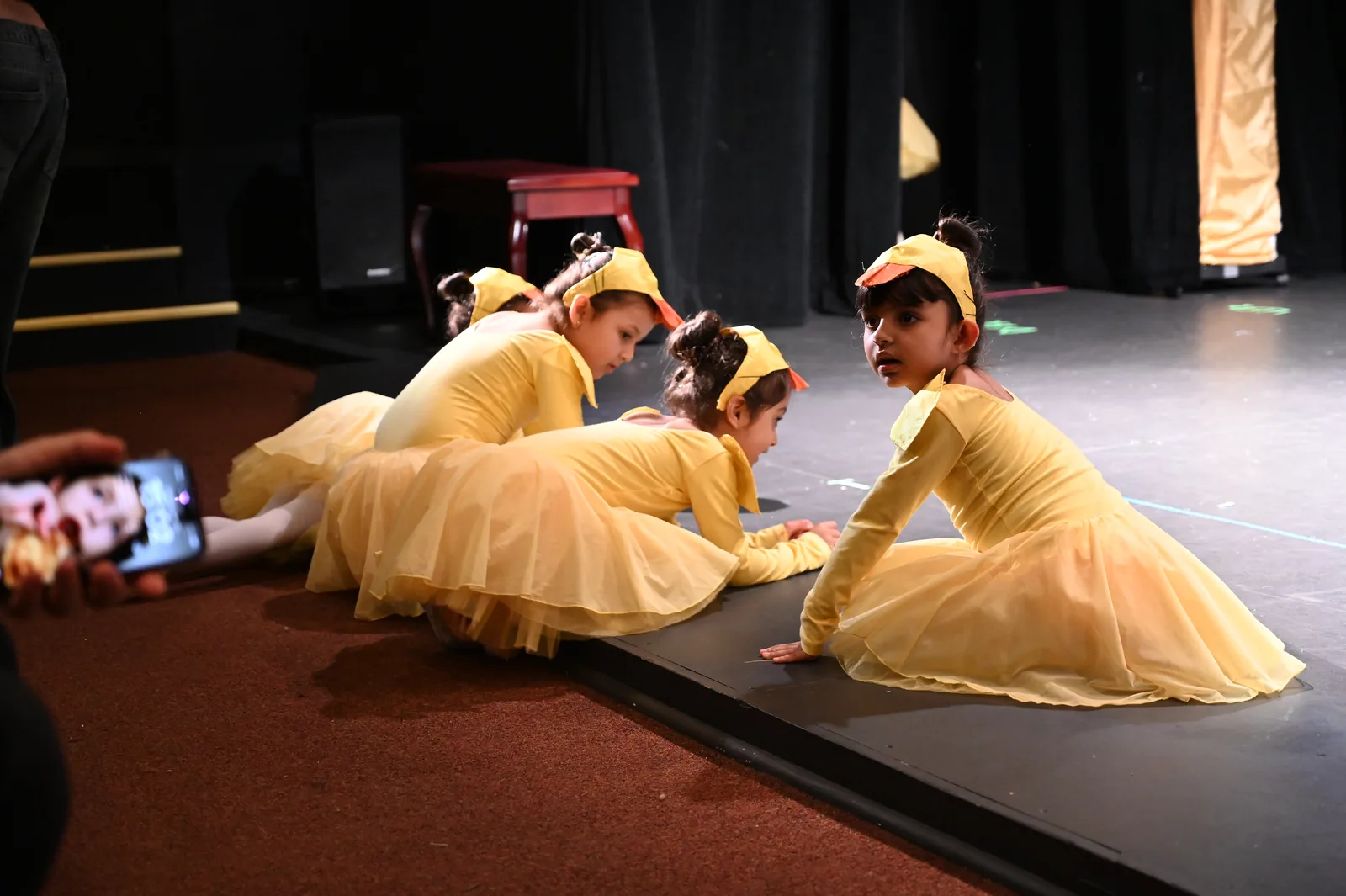 Young dancers in yellow costumes waiting at the edge of the stage