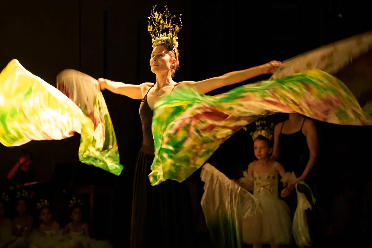 A dancer sweeping painted green silks across the stage as the rose garden